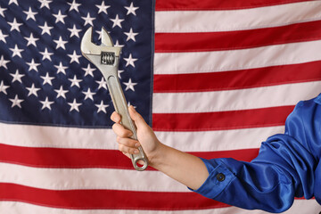 Female worker holding wrench on USA flag background. Labor Day celebration