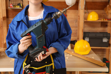Female carpenter with drill in workshop. Labor Day celebration