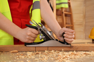 Female carpenter planing plank in workshop, closeup. Labor Day celebration