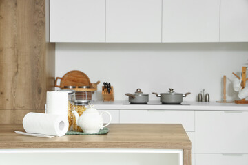 Rolls of paper towels with teapot and food on table in kitchen