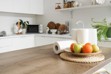 Rolls of paper towels with fruits on table in kitchen, closeup