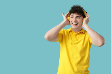 Handsome young man in headphones listening to music on blue background