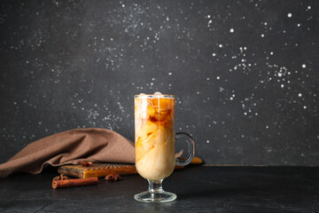 Glass cup of iced latte with cinnamon and star anise on black background