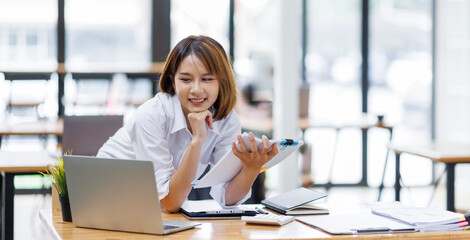 Portrait of happy asian female employee at computer