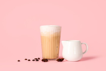 Glass of iced latte with star anise and coffee beans on pink background