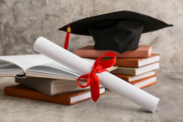 Diploma with books and mortar board on grey background