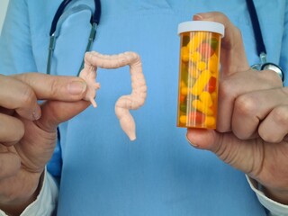 Doctor Holding Model of Human Colon and Prescription Bottle