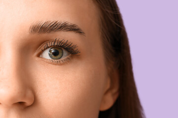 Young woman with beautiful eyebrows on lilac background, closeup