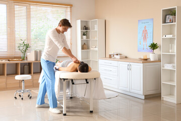 Male therapist massaging young woman with wooden scraper in spa salon