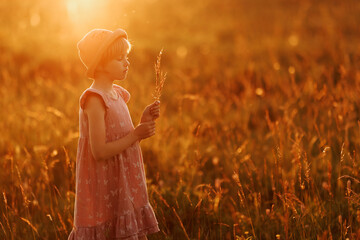 A young girl in a field of flowers, holding a bouquet of spikelets. The scene is peaceful and...