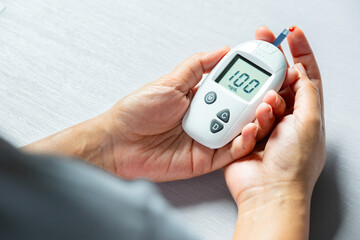 Woman's hands checking diabetes and hyperglycemia with digital blood sugar meter. Healthcare and medical concept	