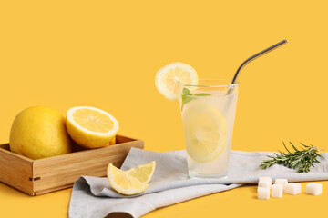 Glass of fresh lemonade with mint and rosemary on yellow background