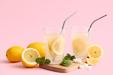 Glasses of fresh lemonade with mint and sugar on pink background