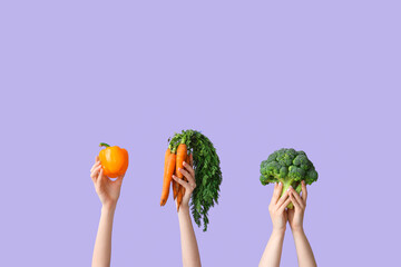 Female hands holding fresh vegetables on lilac background