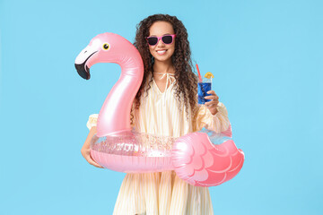 Beautiful young African-American woman with cocktail and inflatable ring in shape of flamingo on...