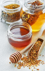 Raw organic bee pollen and honey in jars.