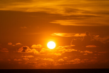 The sun behind the dark clouds, creating breathtaking ray of lights to its surrounding area during the sunset.