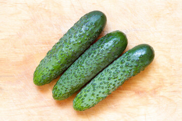 Natural organic cucumbers on a wooden surface. Three green cucumbers. View from above.