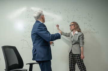 Female student answers a question from an elderly professor at a white board. 