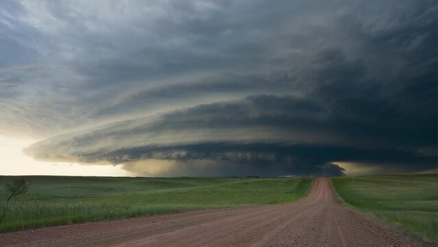 dramatic time-lapse of a supercell thunderstorm forming over a rural landscape, showcasing the dynamic movement of clouds and changing light conditions