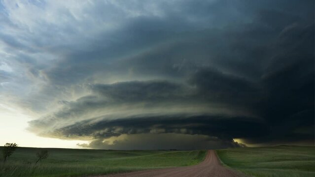 dramatic time-lapse of a supercell thunderstorm forming over a rural landscape, showcasing the dynamic movement of clouds and changing light conditions
