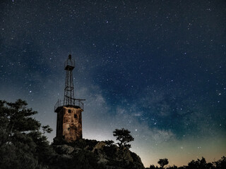 lighthouse under scarry sky at night astrophotography