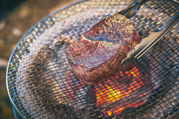 炭火で厚切りステーキを焼く