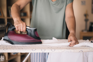 Ironing Clothes At Home.
Female Ironing A White Shirt On An Ironing Board, Representing The Daily...