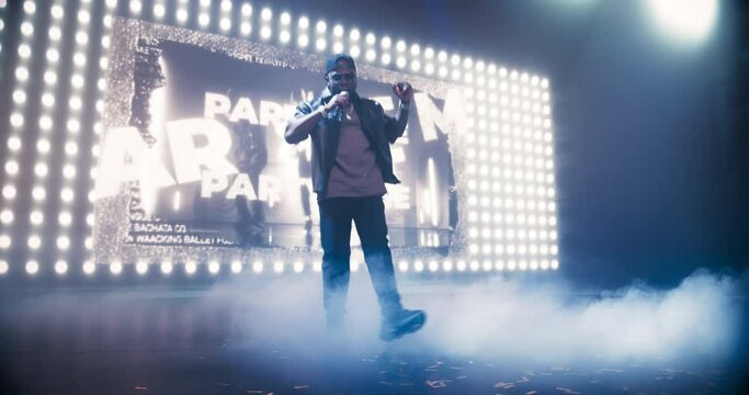 Male Rapper Lights Up the Night With a Creative Performance. Music Artist Enthusiastically Dancing on Stage and Stunning LED Screen Visuals Create a Urban and Underground Atmosphere on Stage