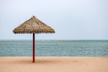 Straw umbrella on the beach in Doha on a cloudy day