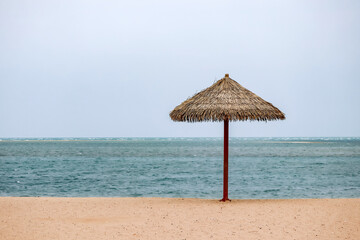 Straw umbrella on the beach in Doha on a cloudy day