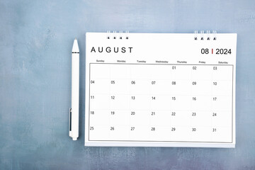 Directly above view of August 2024 desk calendar and pen on wooden background.