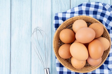 Top view of organic chicken eggs in wooden basket on wooden floor.