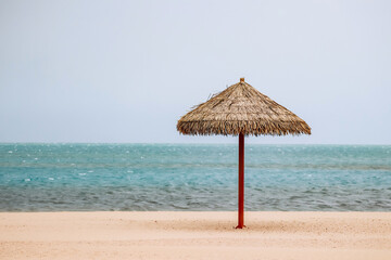 Straw umbrella on the beach in Doha on a cloudy day