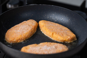 Fish cutlets sizzling in oil while frying in a pan on the stove. Concept of home cooking, traditional recipes, and culinary preparation.