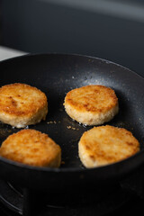 Meatballs or small meat patties cutlets sizzling in oil while frying in a pan on the stove. Concept of home cooking, traditional recipes, and culinary preparation