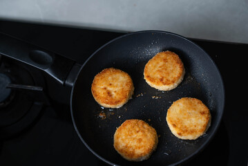 Meatballs or small meat patties cutlets sizzling in oil while frying in a pan on the stove. Concept of home cooking, traditional recipes, and culinary preparation