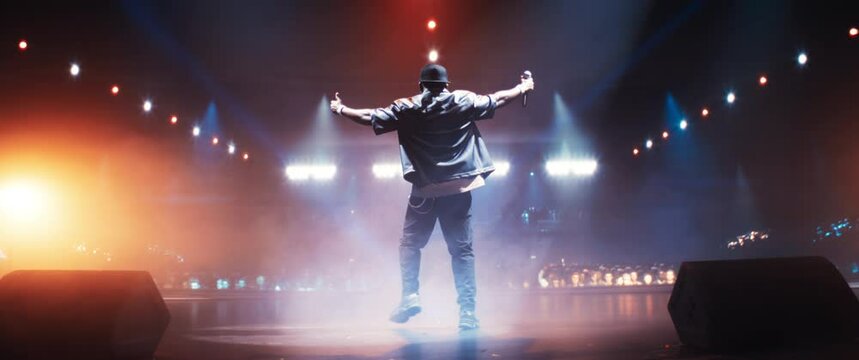Male Rapper Lights Up the Night With a Creative Performance. Music Artist Dancing on Stage, Creating an Urban and Underground Atmosphere on Stage. Footage From the Back. Anamorphic Shot