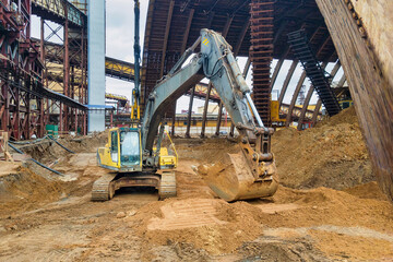Fototapeta premium A excavator with immense power scoops up dirt at a bustling construction site, transforming the landscape with precision and strength