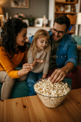 Cheerful family Sitting in the living room and eating the popcorns