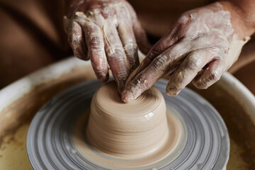 Close up of hands carefully shaping clay on pottery wheel creating unique ceramics copy space