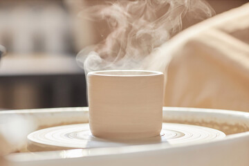 Minimal background image of raw clay piece smoking on pottery wheel in art studio copy space