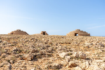Bunkers from the Spanish Civil War next to Punta Nati lighthouse in the north of the island of Menorca, in the Balearic Islands. In the foreground with an arid, rocky landscape and a blue sky