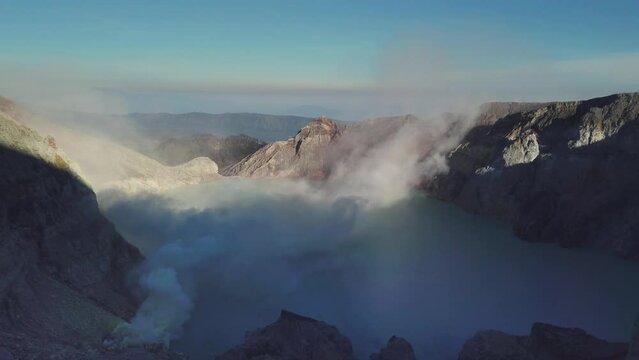Ijen volcano crater, acidic lake and evaporating fumes nn the bright light of early morning sun in Java  island