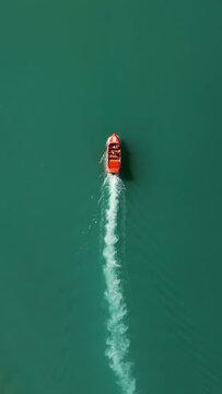 Vertical Screen: This aerial view captures a red speedboat on green water, creating a white trail. Ideal for vertical displays, it showcases vibrant colors and dynamic movement sure to engage viewers