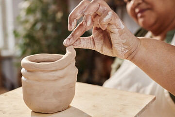 Close up of woman hand shaping ceramic mug enjoying pottery class in art studio copy space