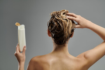 Woman holding a tube of shampoo.