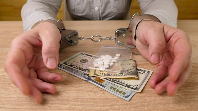 Woman in handcuffs with medicine and dollars. The concept of drug addiction. Drug crime. slow motion