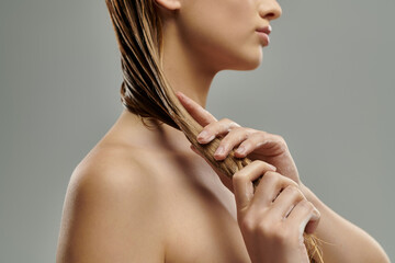 Appealing woman with long hair tenderly applying hair care products.