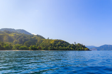 Obraz premium Serene Tropical Escape: Lush Green Islands Rising from Tranquil Blue Waters Under a Clear Sky ; ocean at padang, west sumatra ; indonesia tourism